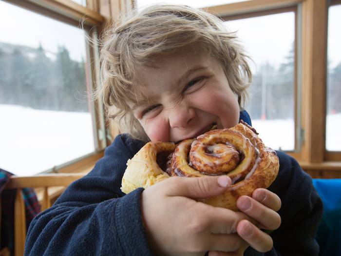 A kid enjoying a cinnamon bun at Sunday River.