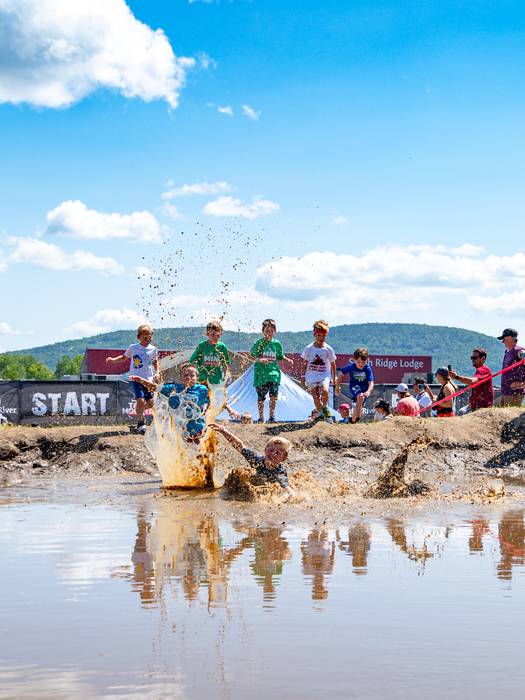 Kids leaping into a pile of muddy water at the Mini Mountain Challenge at Sunday River.