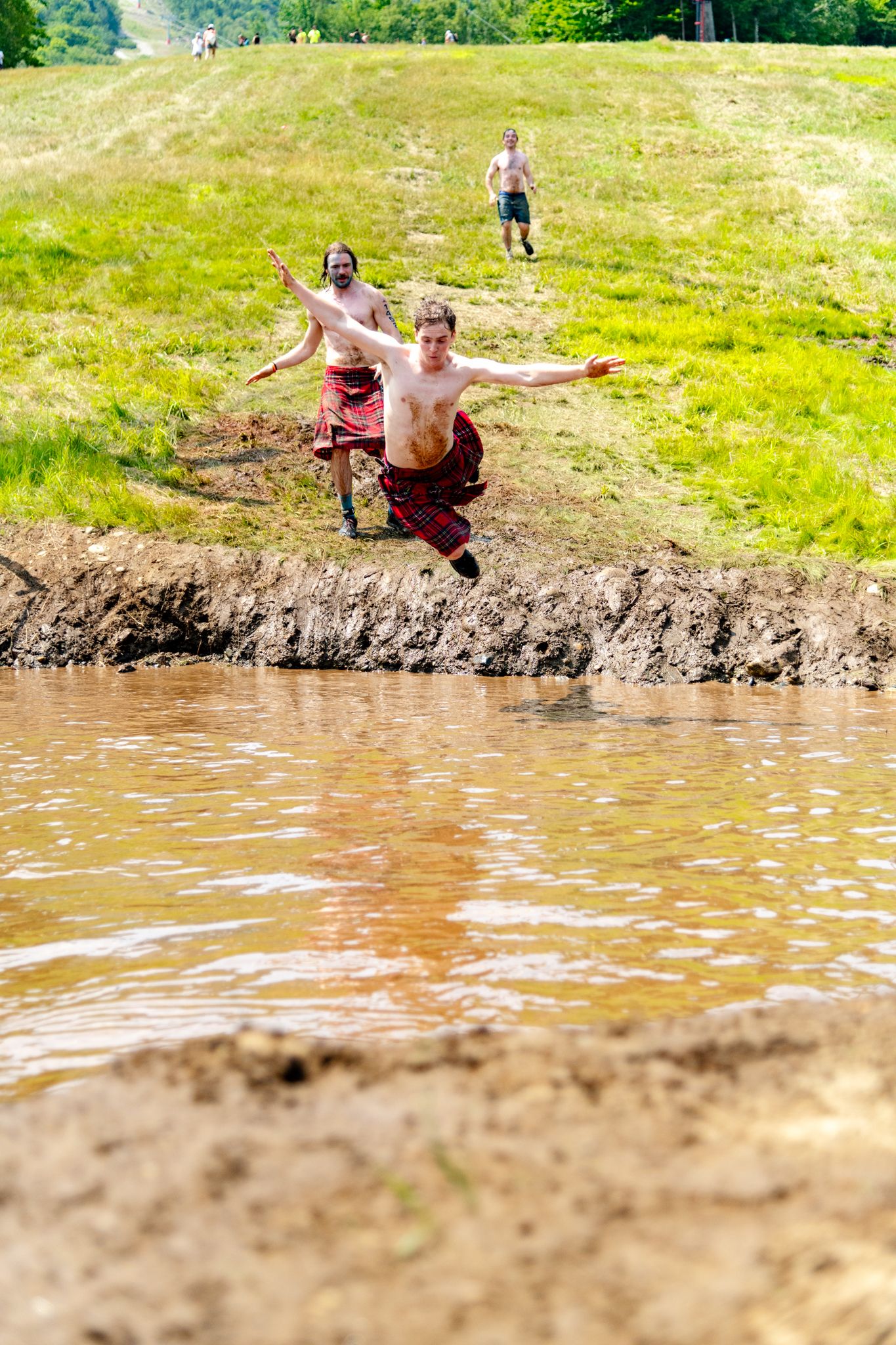 A person flying into a pool of muddy water at the Tough Mountain Challenge at Sunday River.