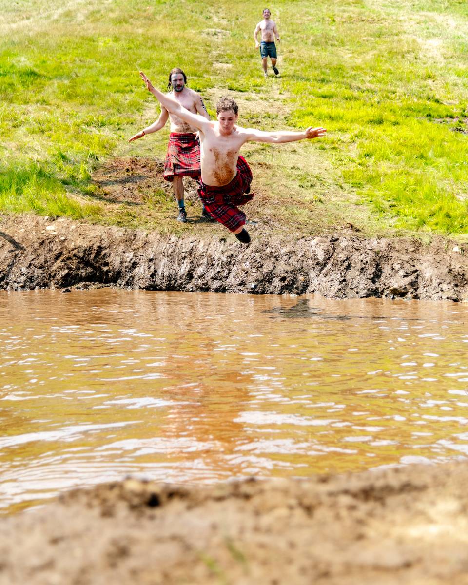 A person flying into a pool of muddy water at the Tough Mountain Challenge at Sunday River.