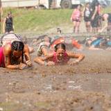 Two girls crawling through mud at Tough Mountain Challenge.