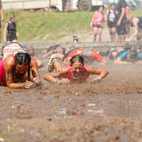Two girls crawling through mud at Tough Mountain Challenge.