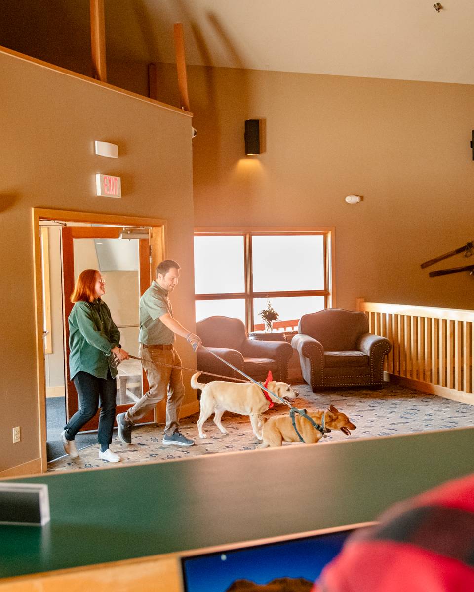 People walking into the Snow Cap Inn with dogs.