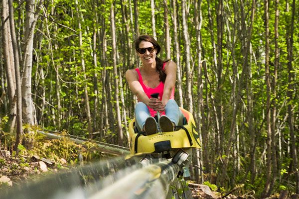 A woman riding on a mountain coaster in the summer time.