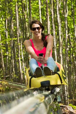 A woman riding on a mountain coaster in the summer time.