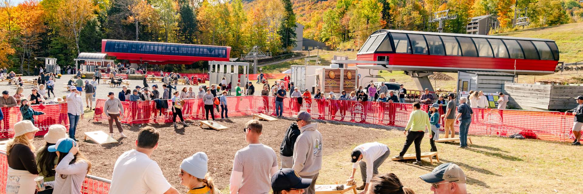 A group of people watching the New England Cornhole tournament at Sunday River's Fall Fest.