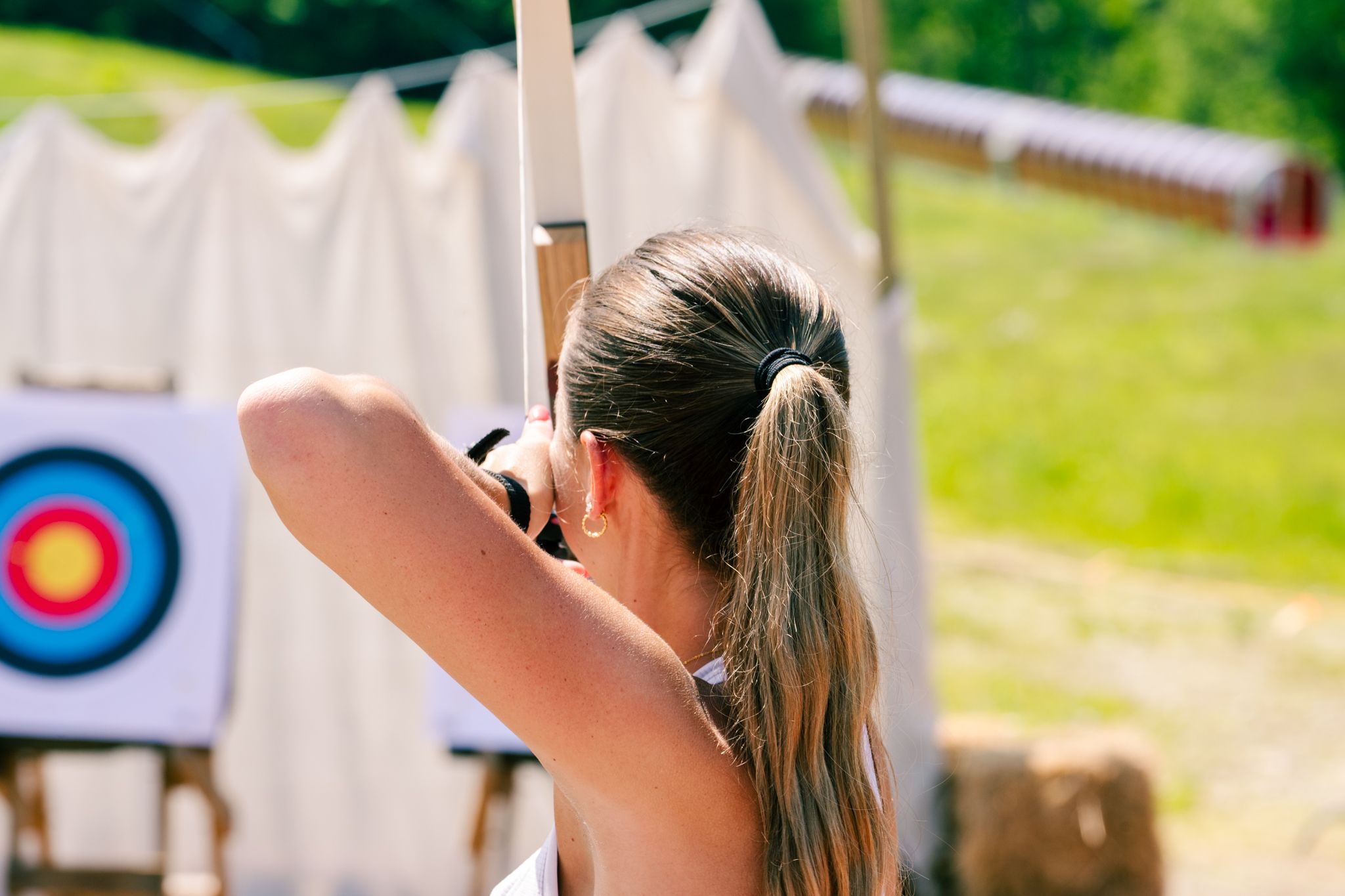 A woman taking an archery lesson at Sunday River Resort.