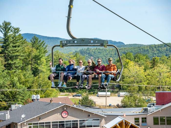 A group of people sitting in a chair on the Chondola for scenic lift rides at Sunday River.