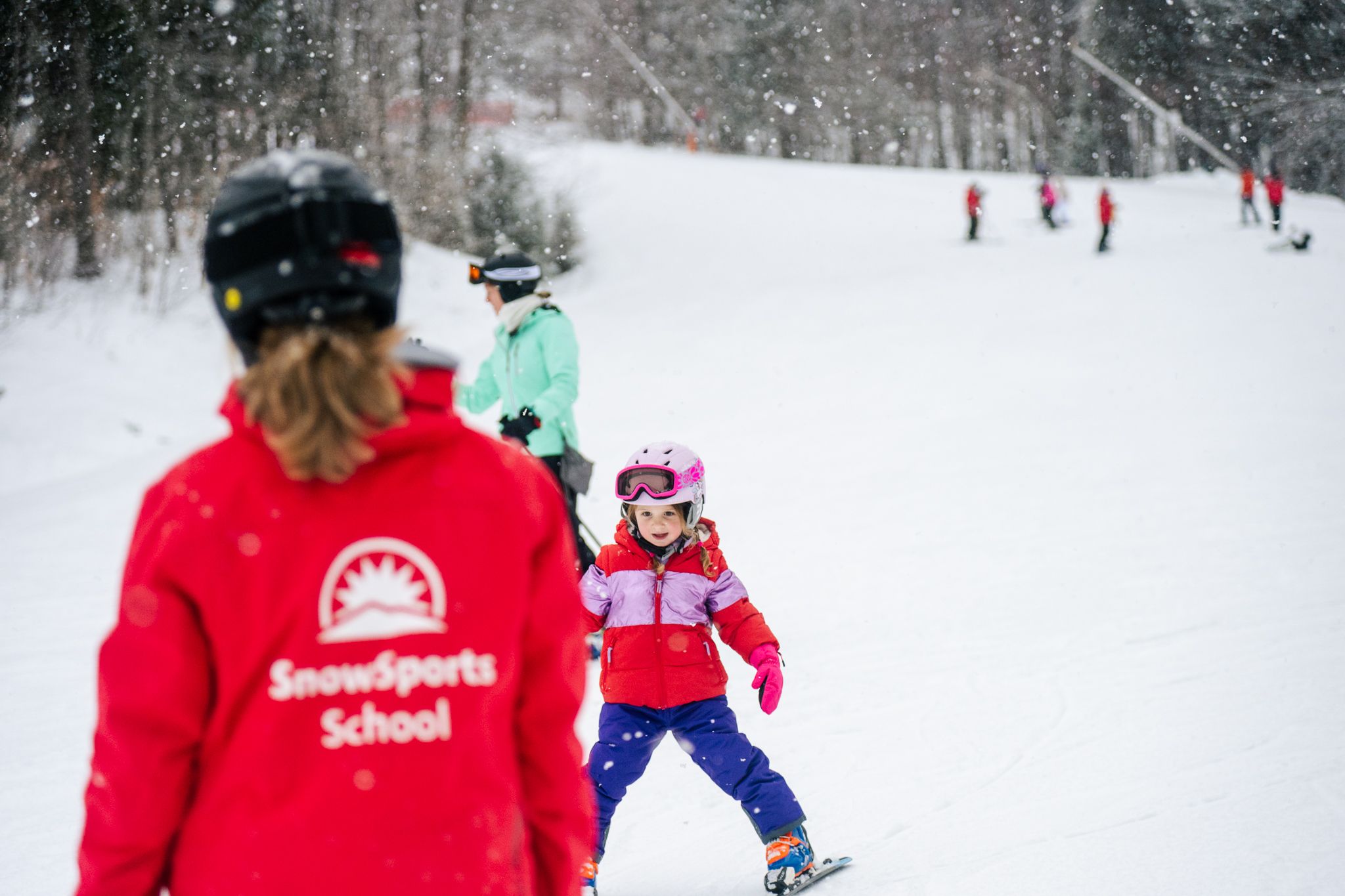An instructor giving a kid a lesson for skiing at Sunday River.