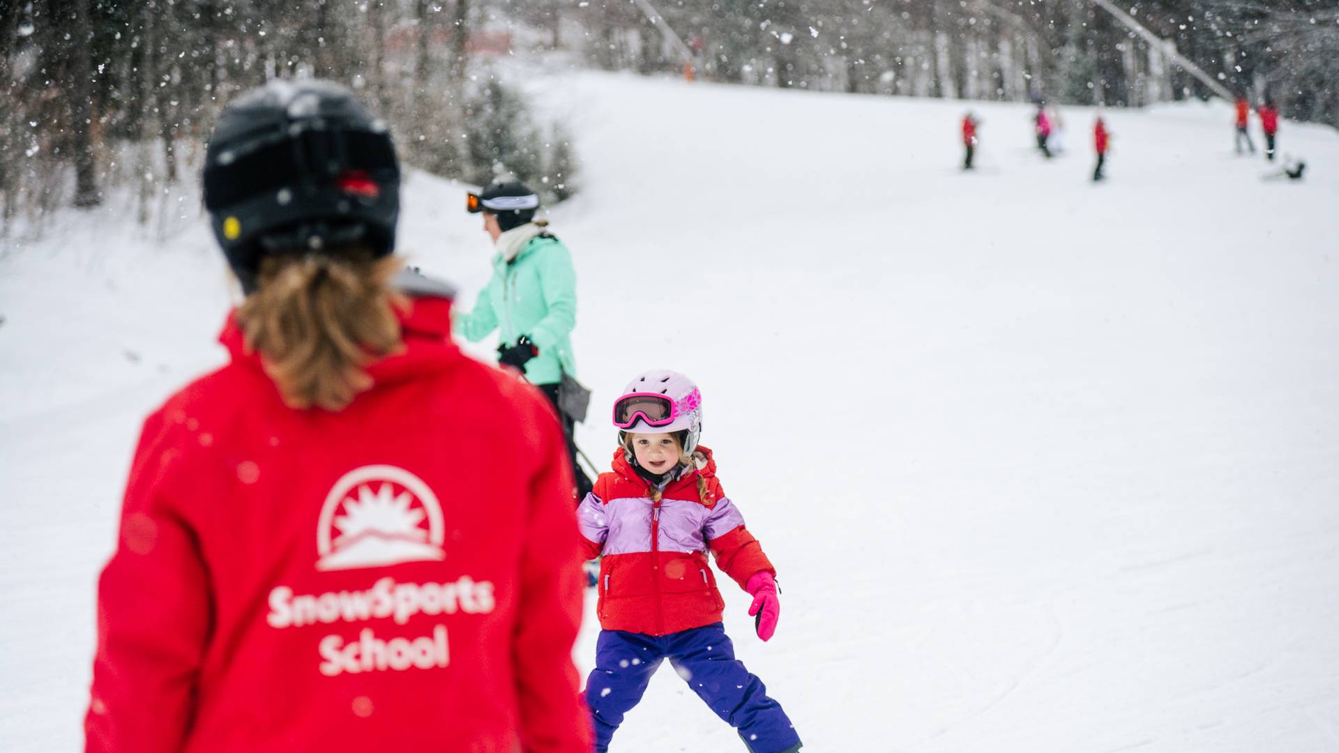 An instructor giving a kid a lesson for skiing at Sunday River.