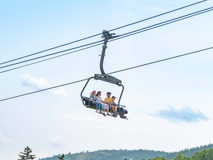 A group of people writing the chairlift at Sunday River in the summer.