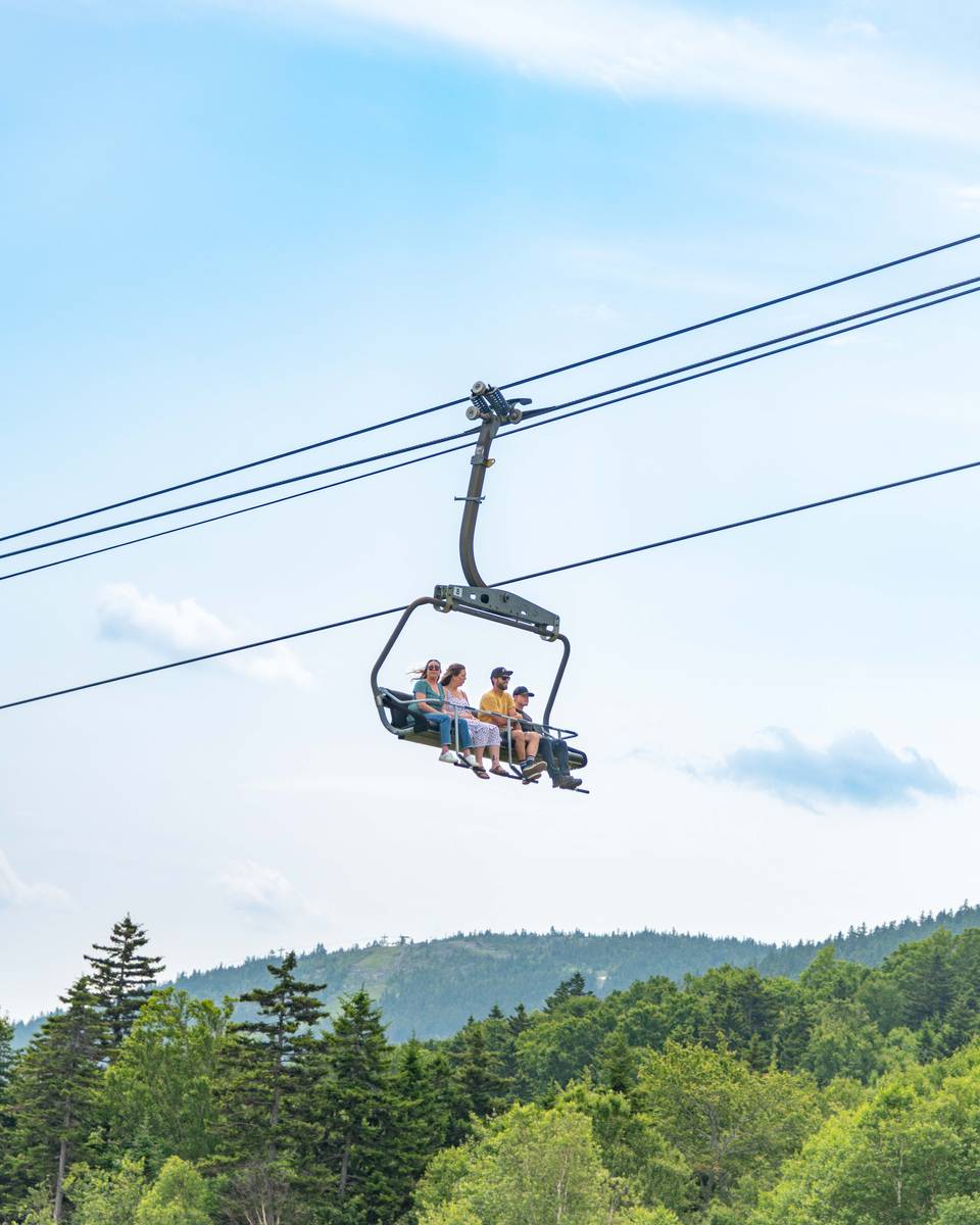 A group of people writing the chairlift at Sunday River in the summer.