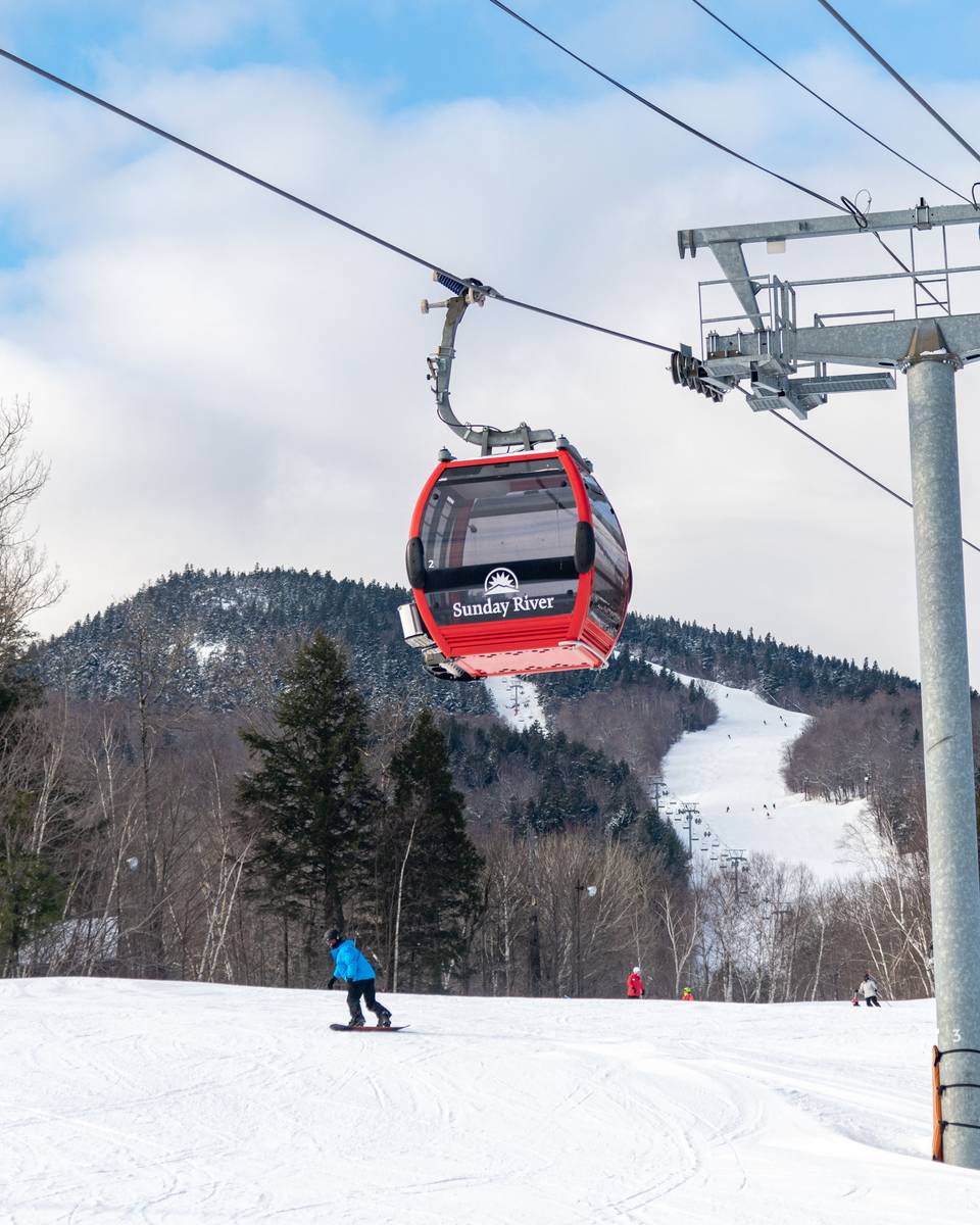 Skiers and snowboarders going under the Chondola chairlift at Sunday River.