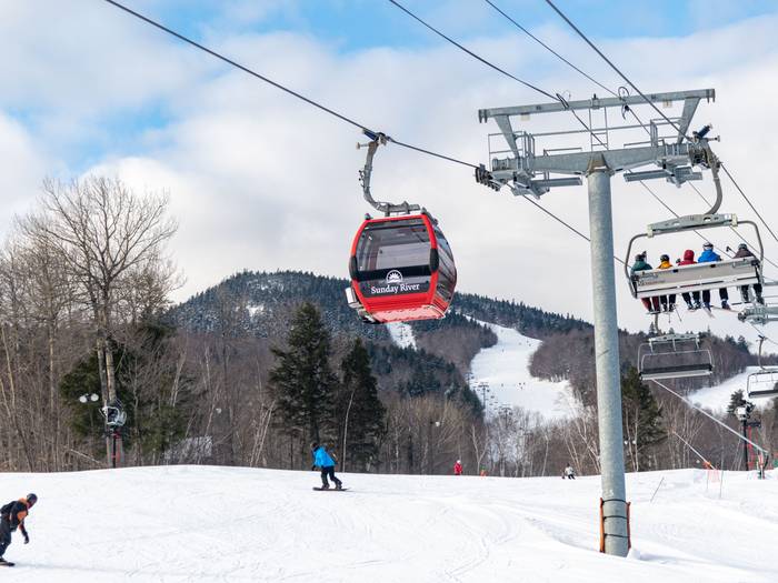 Skiers and riders going down a trail on the Chondola lift line at Sunday River.