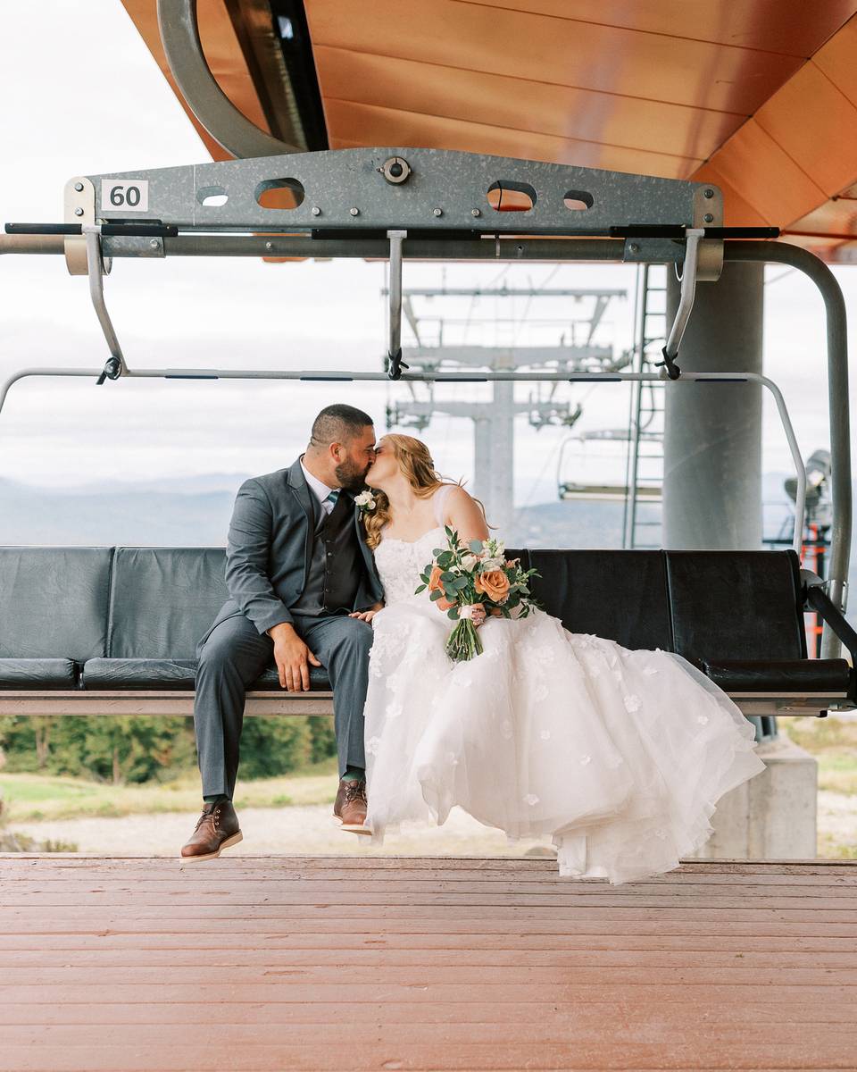 Husband and wife kissing on a chairlift.