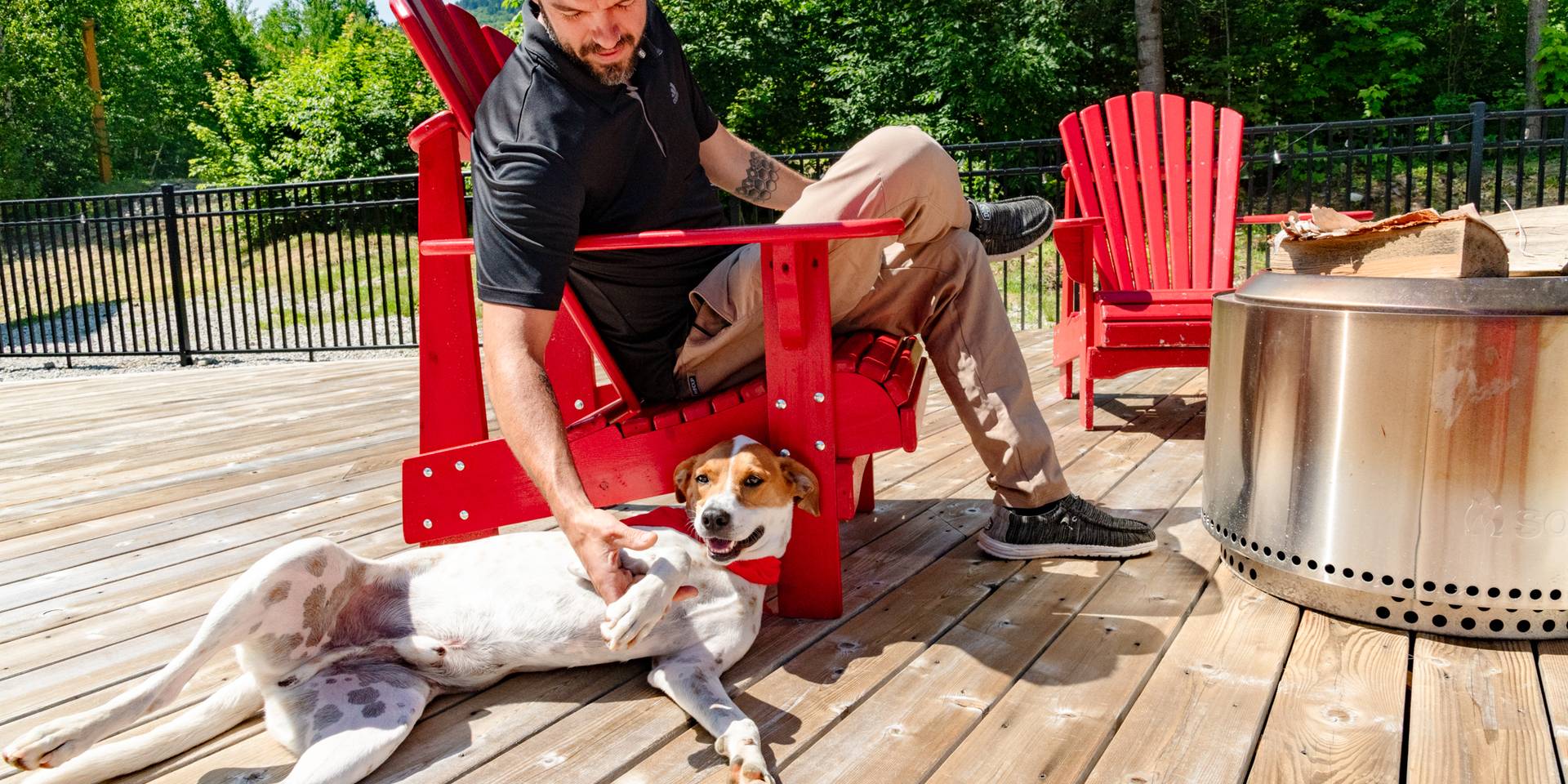 A man and a dog sitting on the deck at the Snow Cap Inn during the summer time.