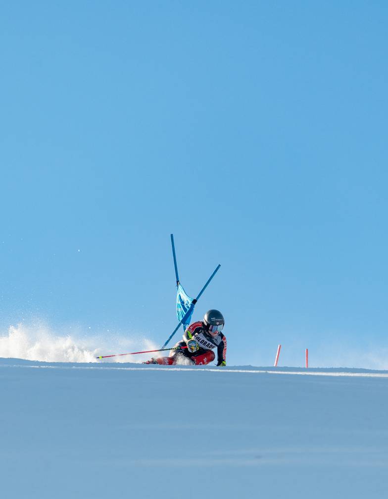 Skier carving to turn against a ski gate at Sunday River.