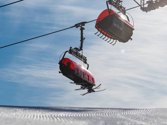 Skiers sitting on Jordan 8 chairlift at Sunday River.