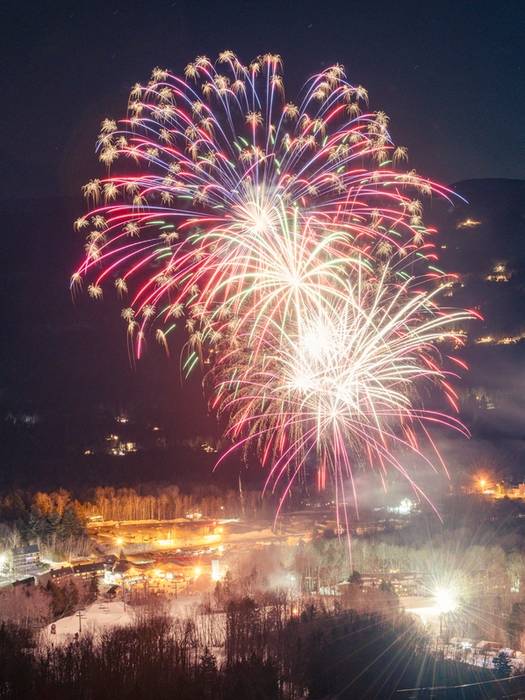 Fireworks exploding over Sunday River in the winter during a fireworks show.