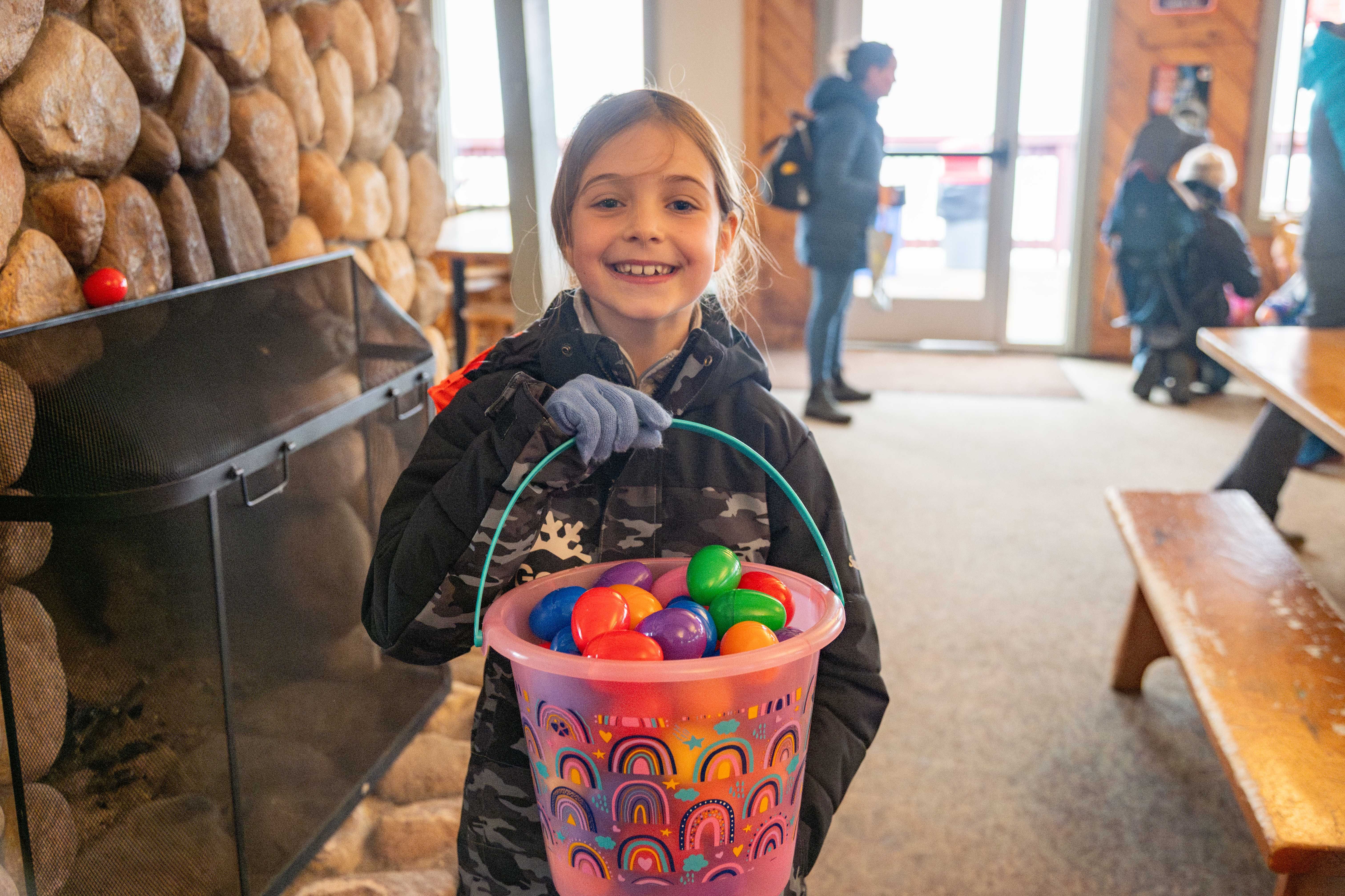 A little girl holding a bucket of Easter Eggs.