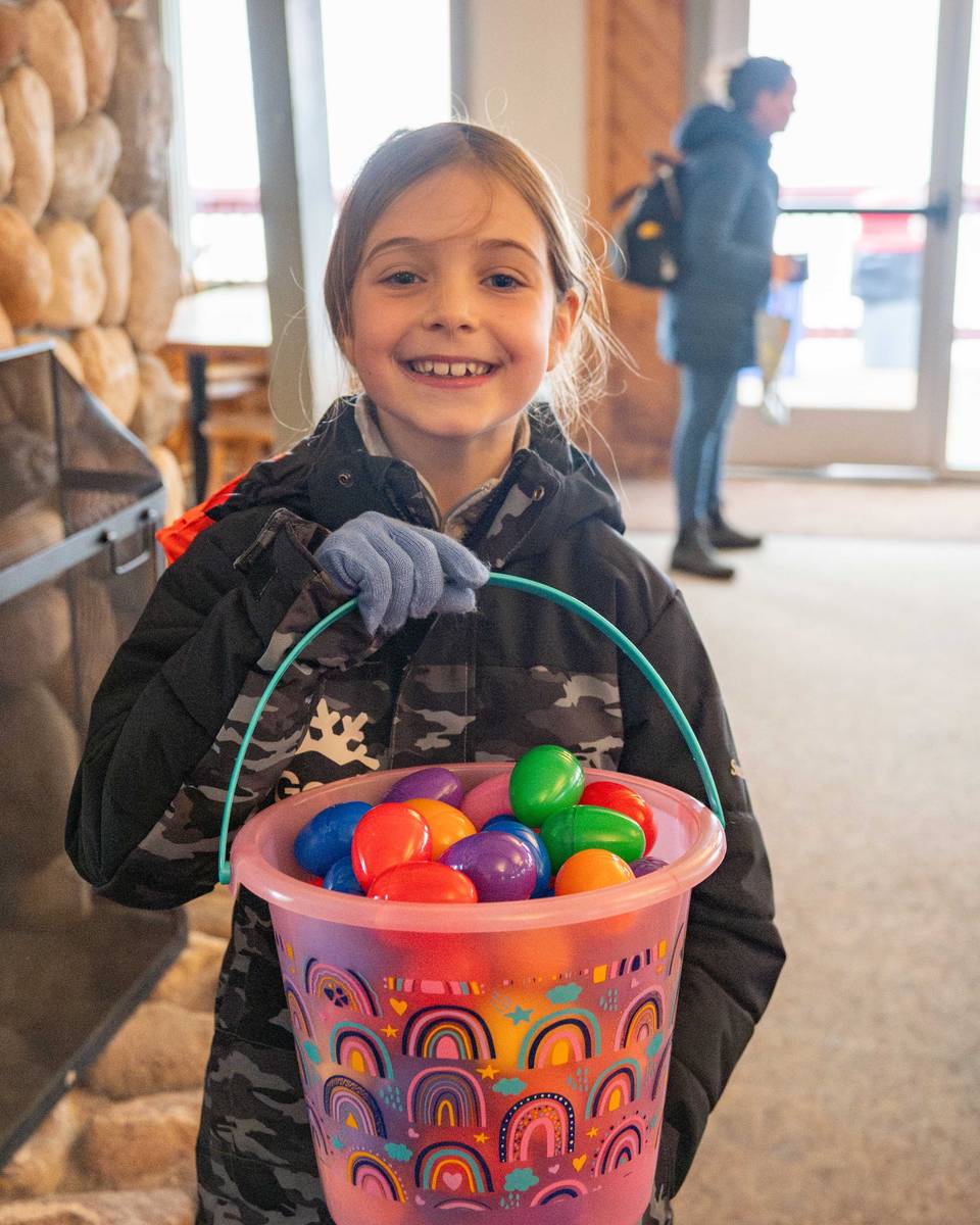 A little girl holding a bucket of Easter Eggs.