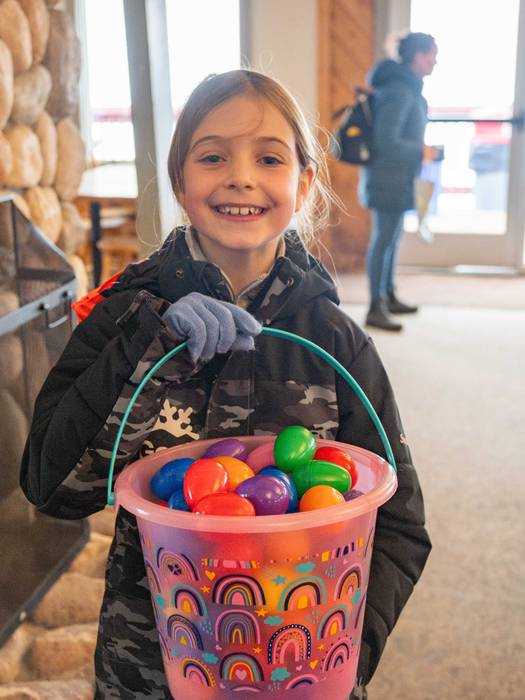 A little girl holding a bucket of Easter Eggs.