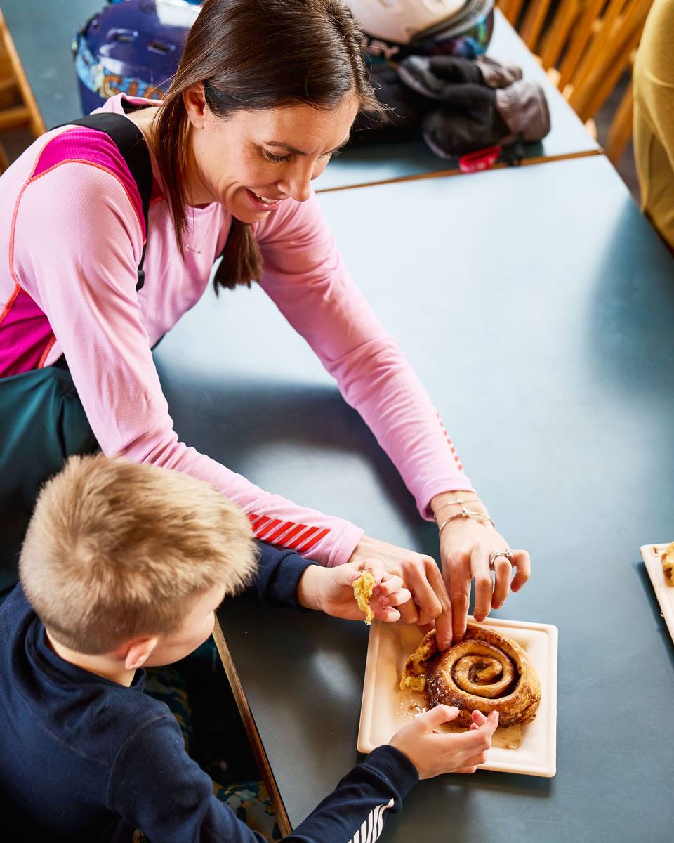 A child and mother share a cinnamon bun at Sunday River.