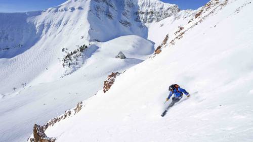 A person skiing down a steep trail in the winter.