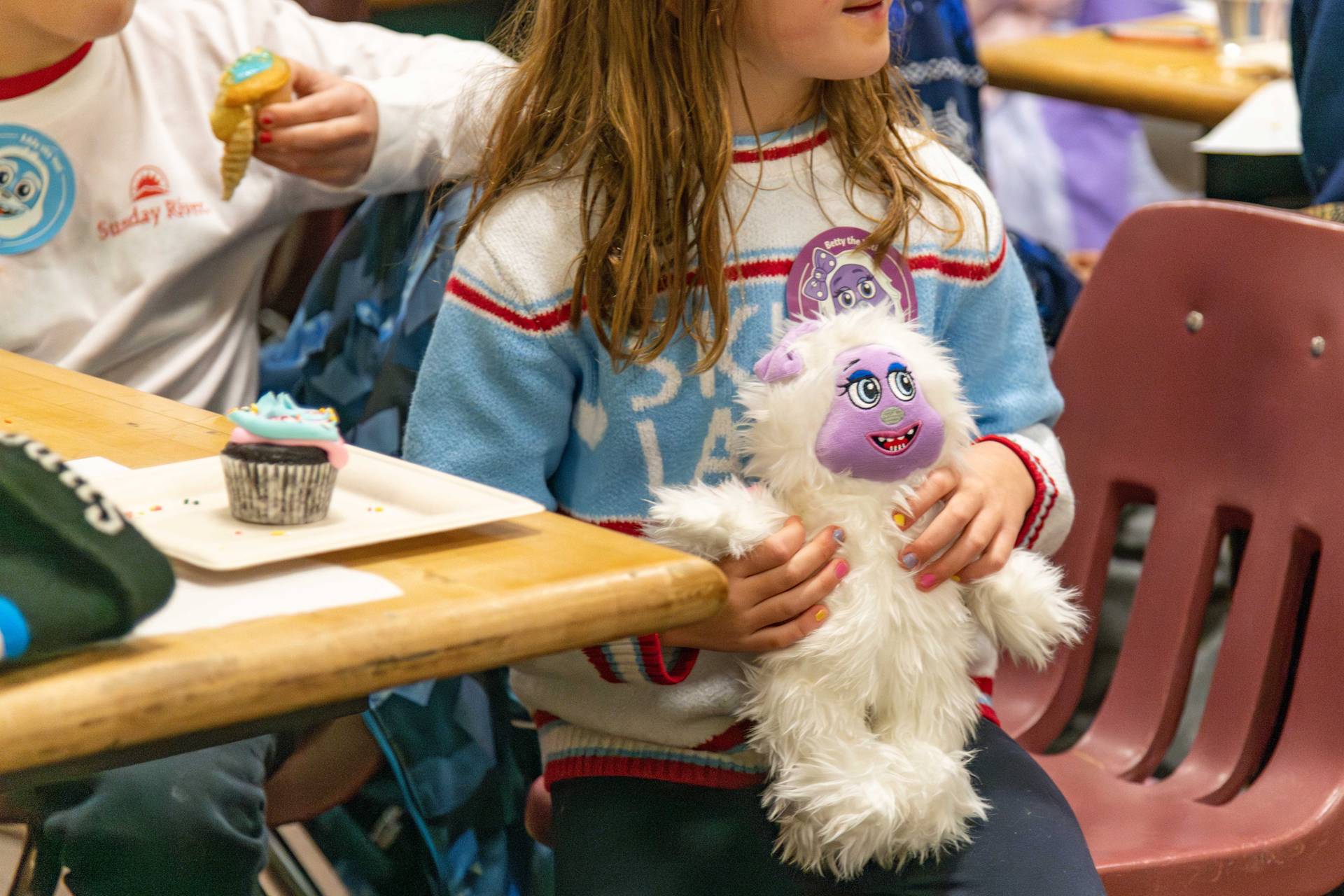 A little girl with her cupcake holding a Betty the Yeti plushy at Sunday River.