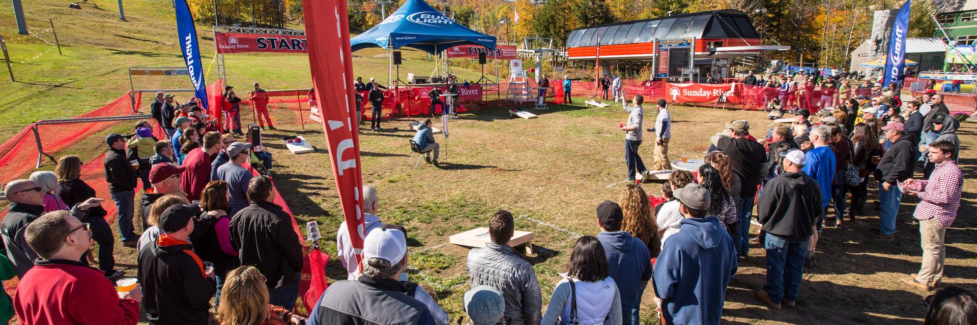A group of people watching the New England Cornhole tournament at Sunday River's Fall Fest.