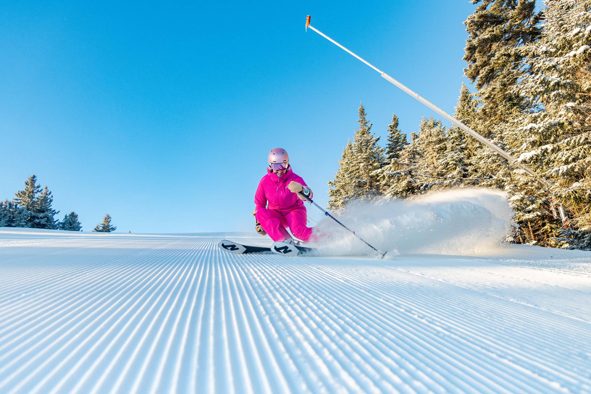 A woman skiing down a trail in a pink ski suit at Sunday River.