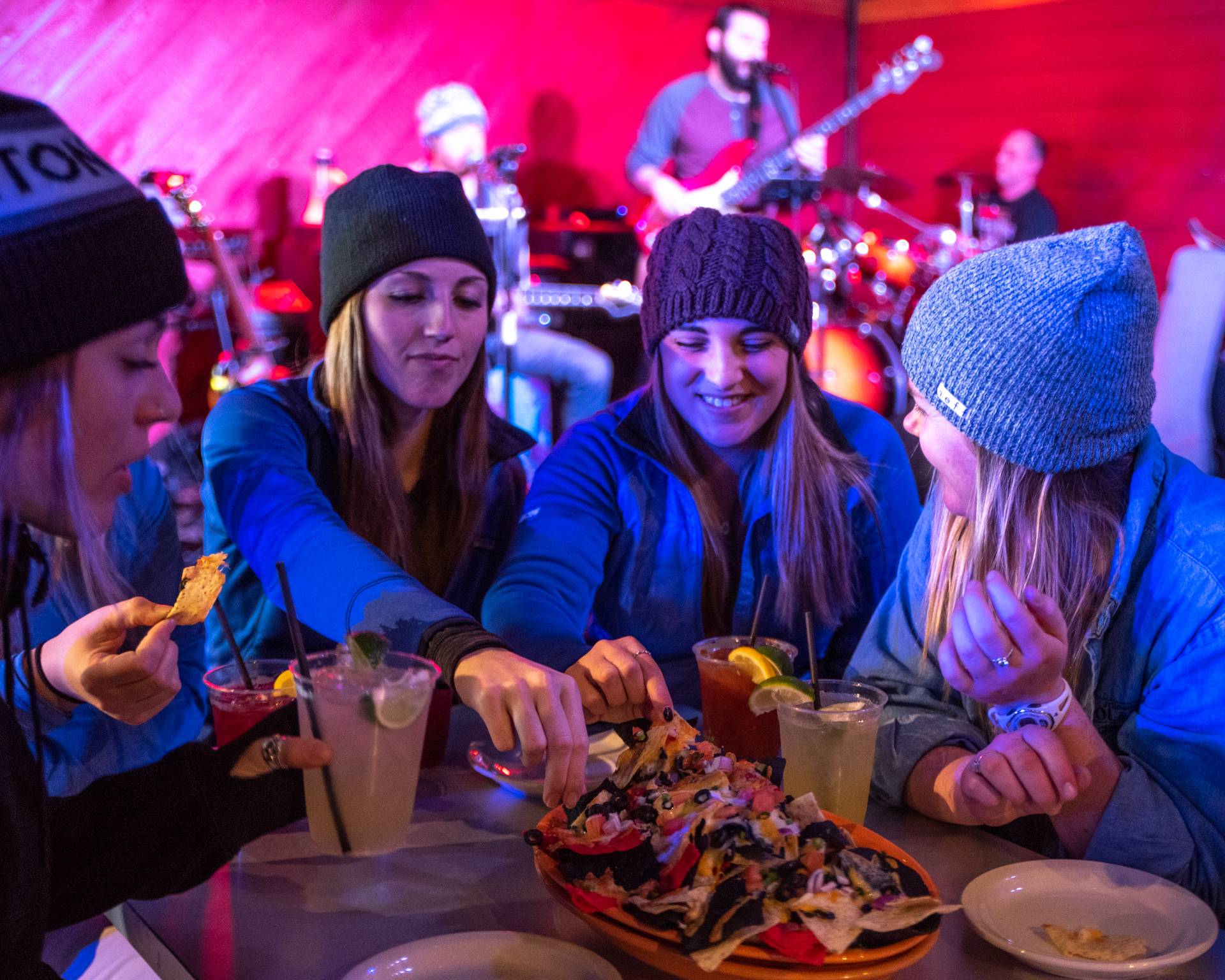 A group of women sitting at a table, enjoying nachos, at Sunday River's Foggy Goggle Restaurant.
