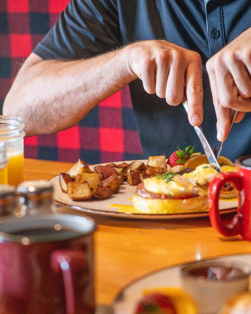 A man cutting into eggs at Camp at Sunday River.