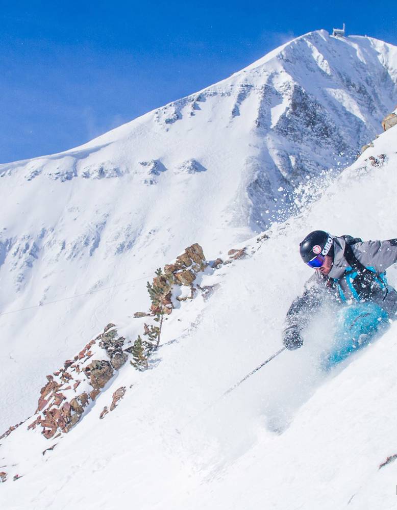 A skier skiing powder on the edge of a mountain