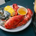 A lobster served with corn on the cob.