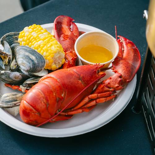 A lobster served with corn on the cob.