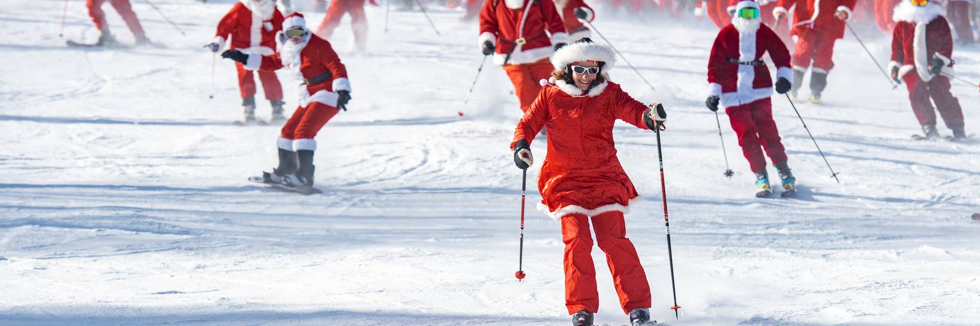 A group of skiiers skiing down a trail wearing Santa suits at Sunday River.