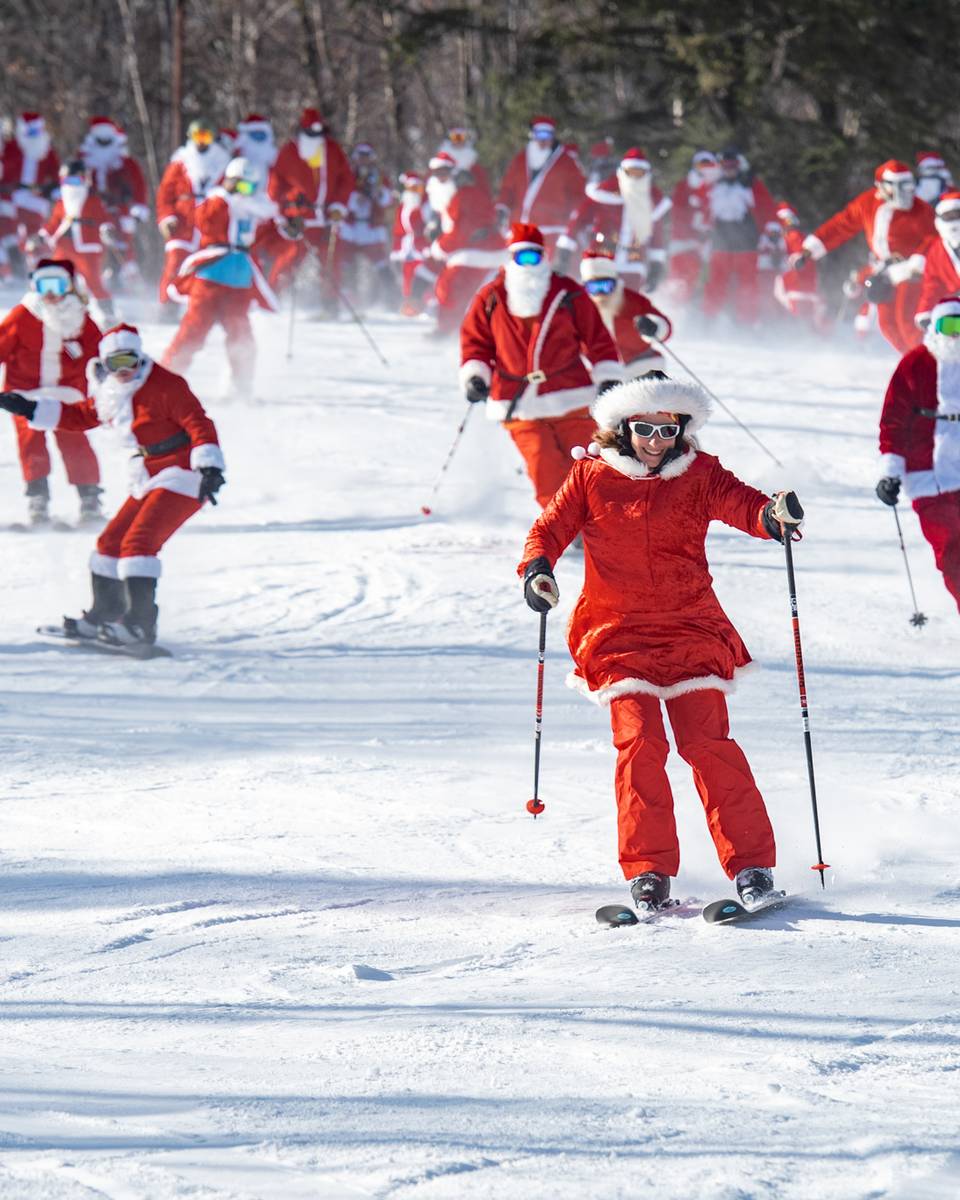 People skiing down a trail dressed as santa.