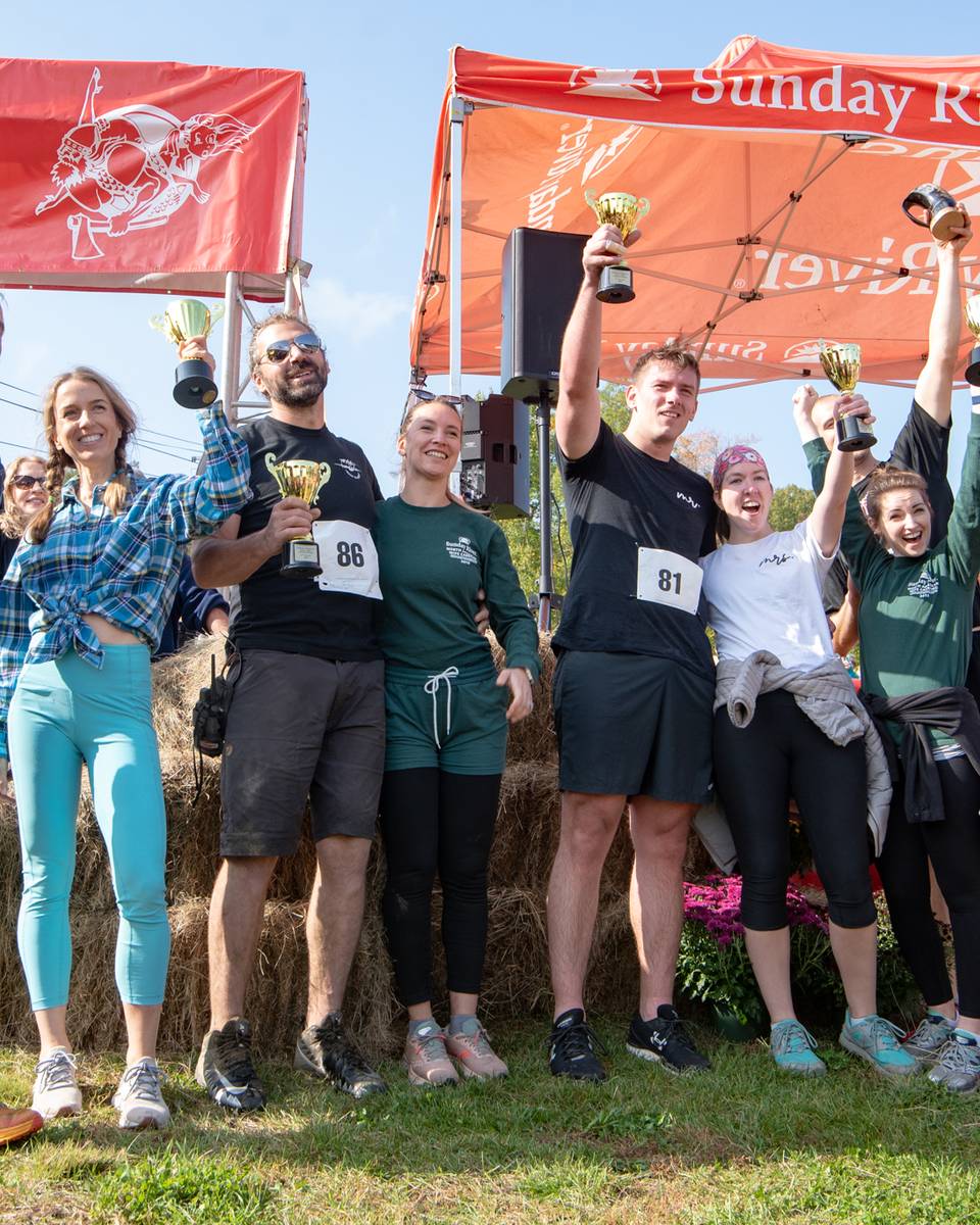 The winners of the North American Wife Carrying Championship holding trophies at Sunday River.