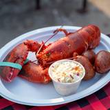 A lobster served with corn on the cob.