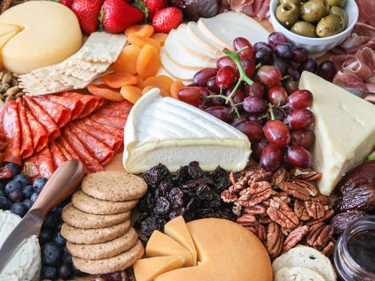 A cheese and fruit spread on a board.
