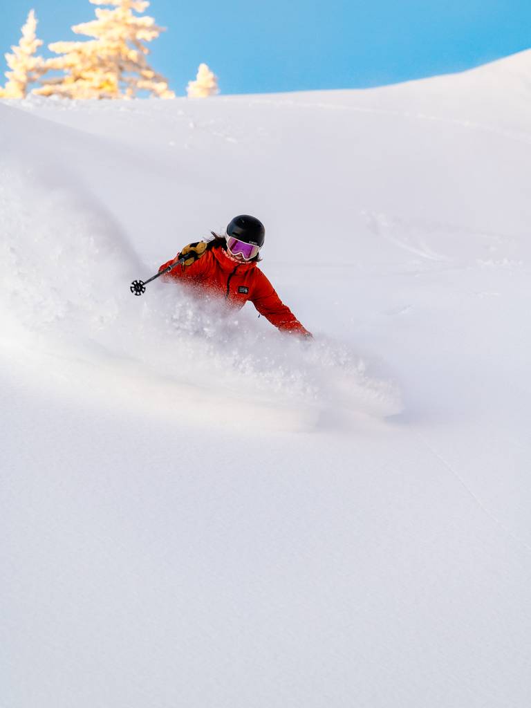 A person skiing in powder at Sunday River.