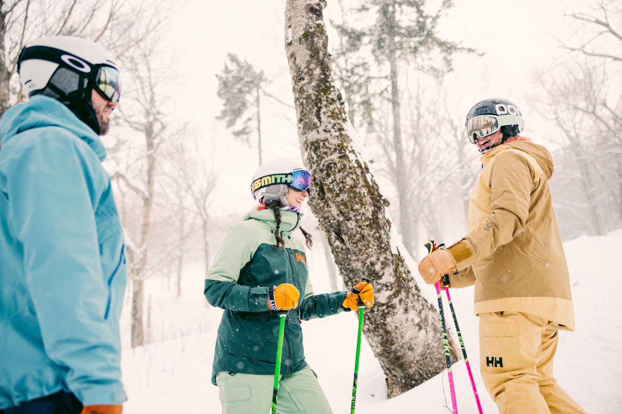A group of skiers and riders stopping for a moment in the woods as snow is falling.