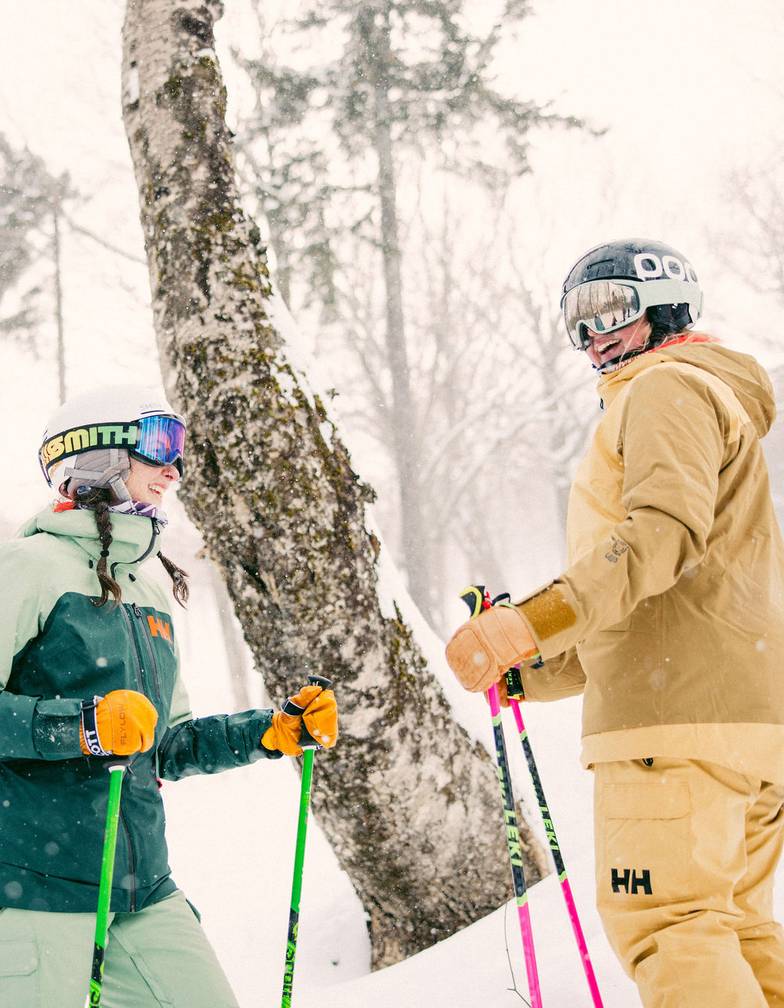 Two skiers talking and laughing on the slopes at Sunday River