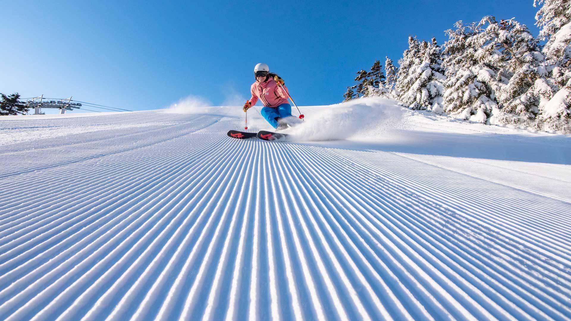 A woman skiing down a trail at Sunday River with powder.