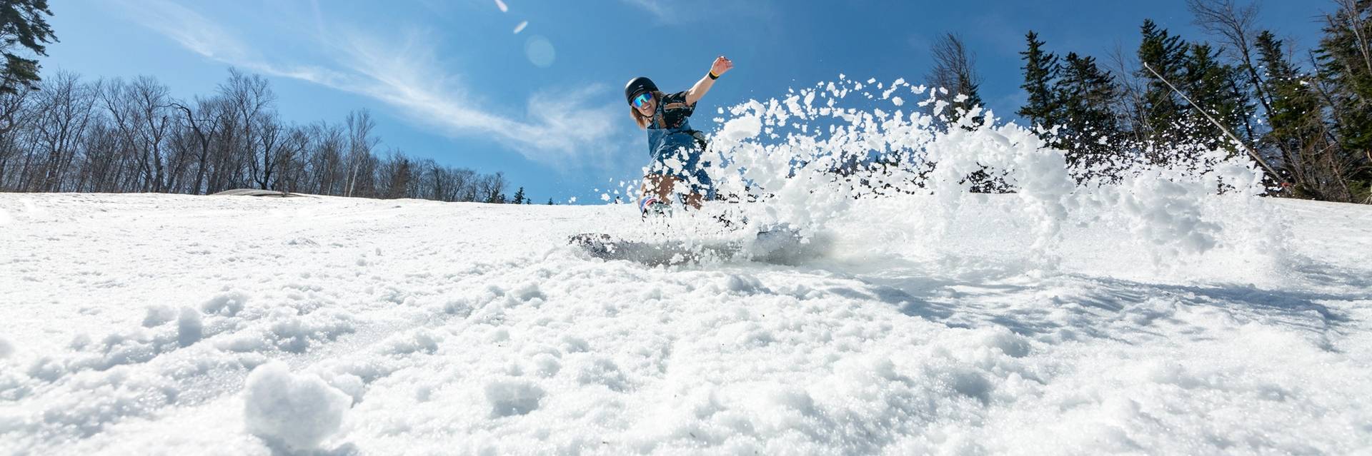 A snowboarder carving up the spring slopes at Sunday River.