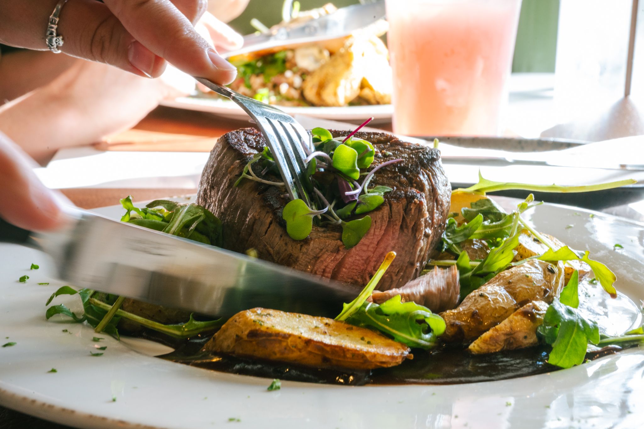 A person cutting into their steak at Ember.