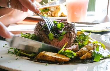 A person cutting their steak at Ember.