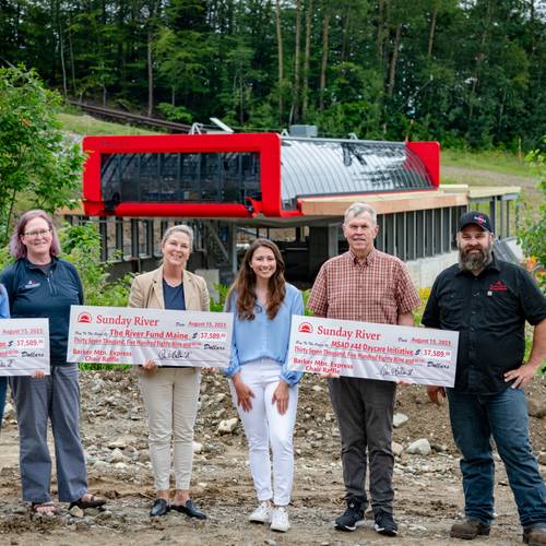 People standing together during a check presentation to local organizations at Sunday River.