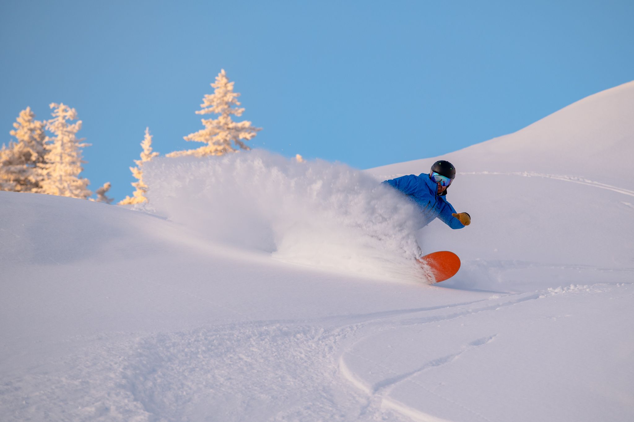 A snowboarder cruising in powder at Sunday River.